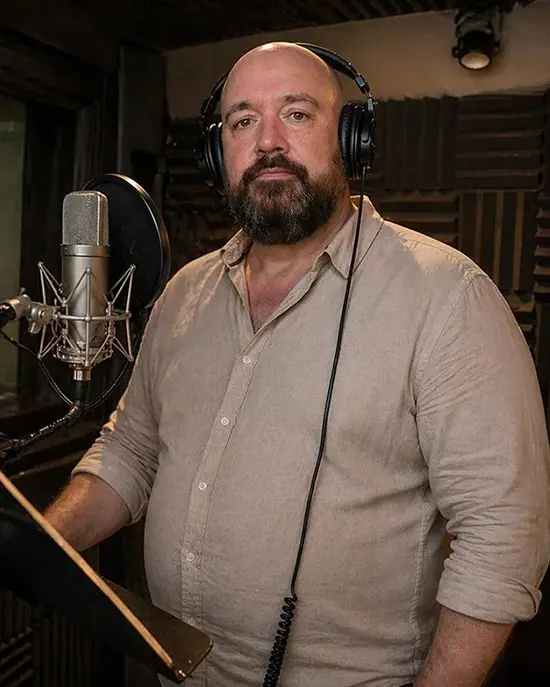 Eric Dieperink met koptelefoon en studiomicrofoon in een opnamebooth